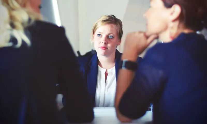 A person at a table being interviewed by two interviewers